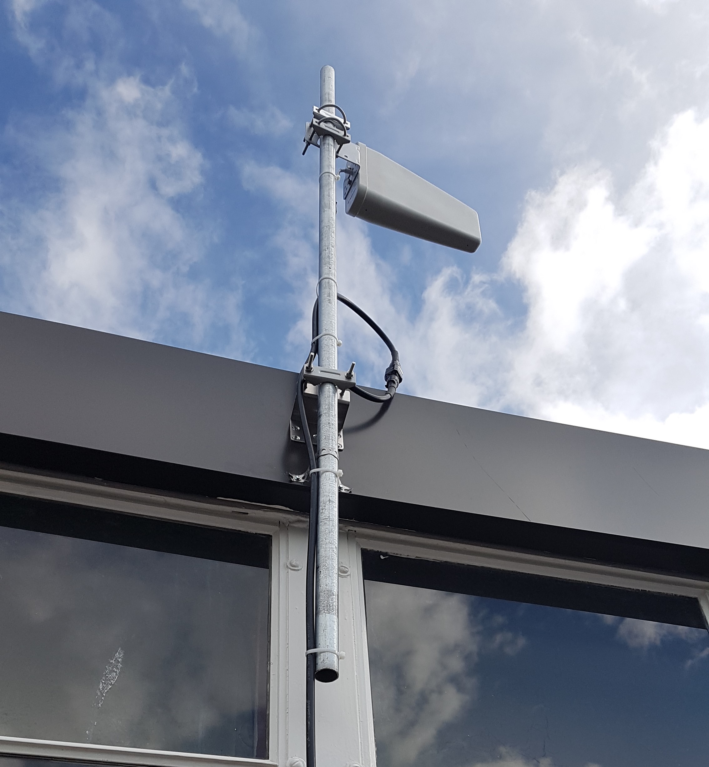 Cell phone signal booster antenna mounted on exterior mast